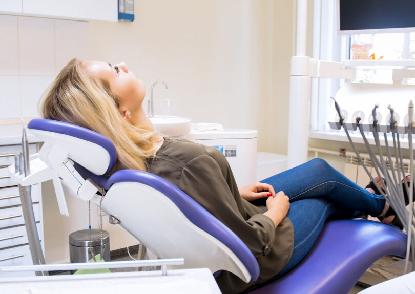 Beautiful woman lying in dentist chair and waiting for doctor